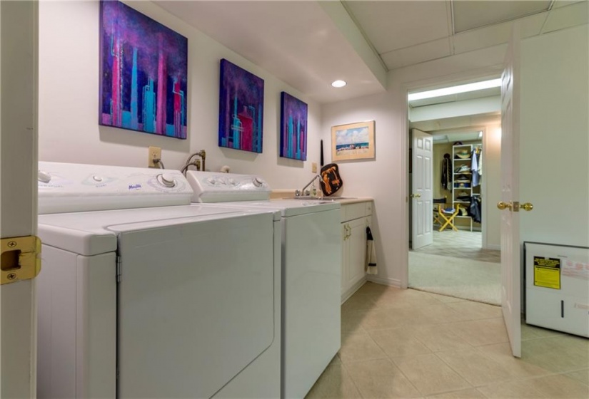 The lower level laundry is a fully finished space featuring wall-to-wall storage cabinets and folding counter. This space could alternatively be converted to an additional lower level summer kitchen.