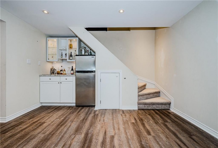 Downstairs, you'll find a handy wet bar tucked under the stairs making for a great use of space in the large rec room.