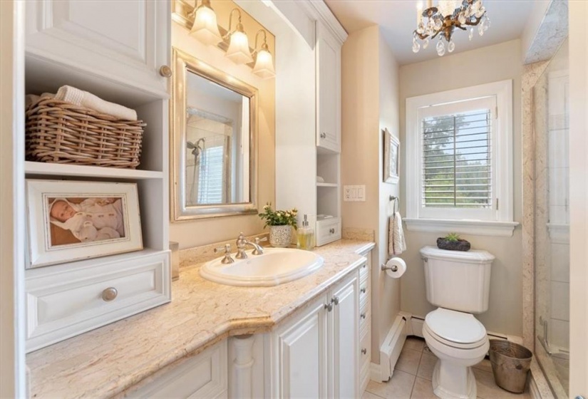 Main bathroom, marble countertop, tile floor. Updated faucets and shower head. Kohler toilet and sink. Extensive white built in cabinetry. Antique chandelier.