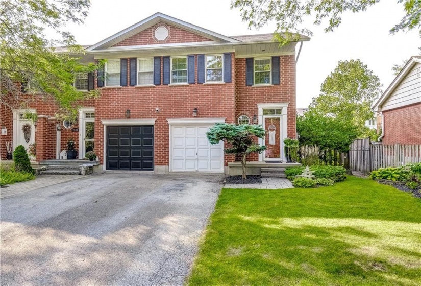 Street view. End unit with tasteful landscaping and driveway 3 cars long