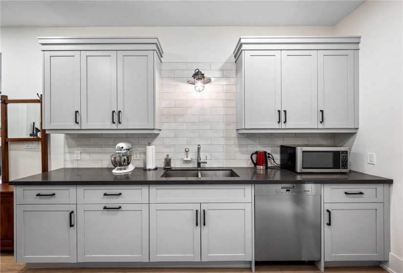 Kitchen on main-floor: double undermount sink, quartz countertops, patterned subway tile backsplash, Miele dishwasher