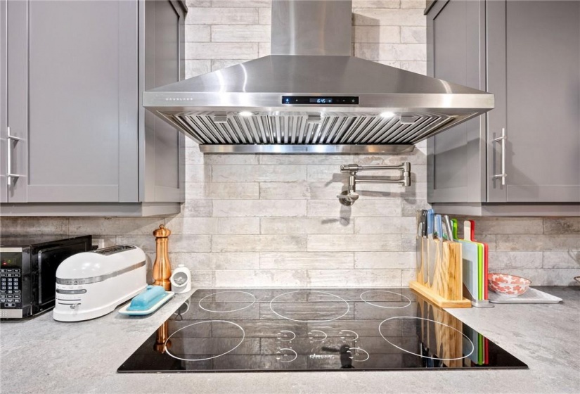 Kitchen in upper unit (2nd flr). Built-in stove top with hood vent and pot-filler! Patterned subway tile backsplash