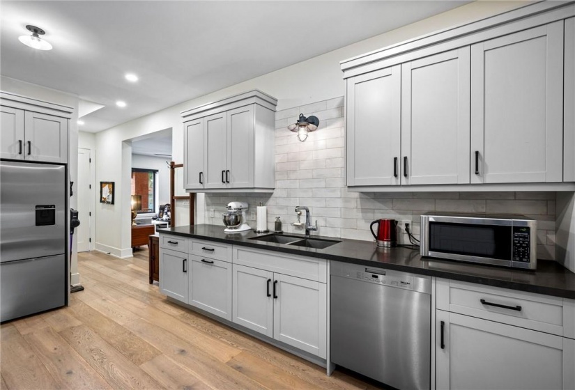 Kitchen on main-floor: double undermount sink, quartz countertops, patterned subway tile backsplash, Miele dishwasher