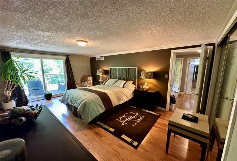 Master bedroom with a walkout to a large deck overlooking the tranquil backyard